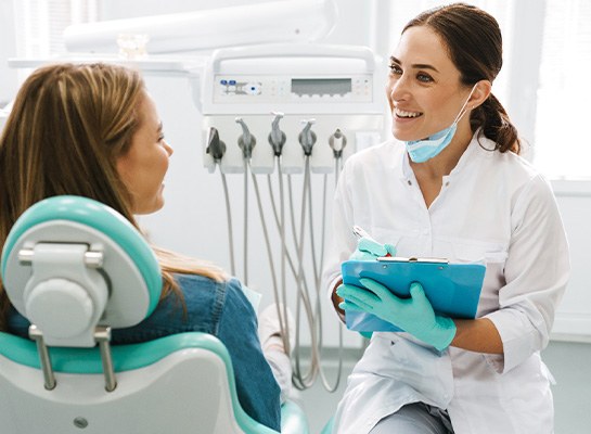 Dentist smiling while taking notes on clipboard