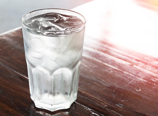 Glass of water with ice cubes on wood table
