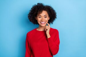 Woman in red touching one finger to her smile